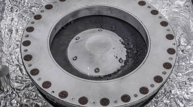 The outside of the OSIRIS-REx sample collector. Sample material from the asteroid Bennu can be seen on the middle right.