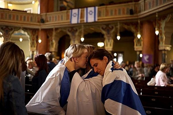 Women wrapped in the Israeli flag react at the end of a prayer for peace at the Sofia Synagogue. (Reuters)