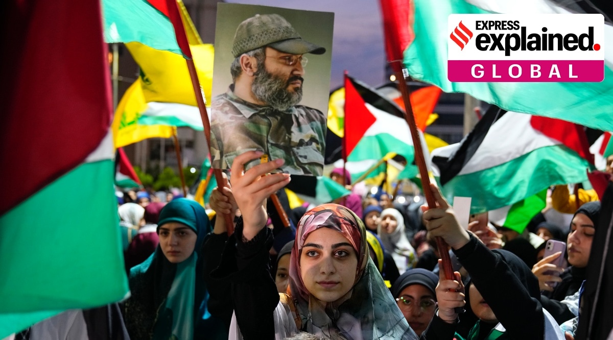 A Hezbollah supporter holds up a poster of the late Hezbollah military commander Imad Mughniyeh, as others wave the group's and Palestinian flags during a rally in celebration of the attacks that the militant Hamas group carried out against Israel, in Dahiyeh, Lebanon, Saturday, Oct. 7, 2023.
