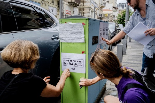 Activists from Standing Together replace signs that call for escalation in the fighting with posters championing solidarity between Jews and Arabs in Haifa, Israel, on Oct. 18, 2023. Long derided as naïve, even traitors, the bridge builders between Israelis and Palestinians sense opportunity in the aftermath of the Hamas attack. (Amit Elkayam/The New York Times)