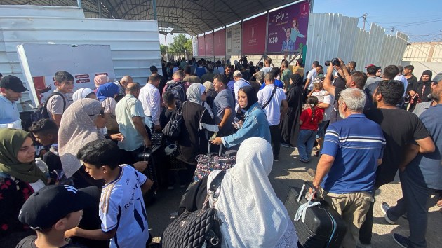 Palestinians with dual citizenship walk at the Rafah border crossing with Egypt, in the hope of getting permission to leave Gaza