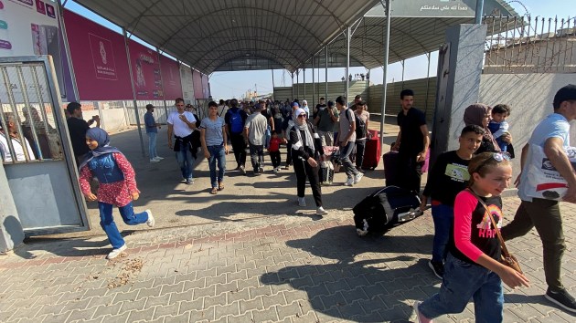 Palestinians with dual citizenship walk at the Rafah border crossing with Egypt, in the hope of getting permission to leave Gaza