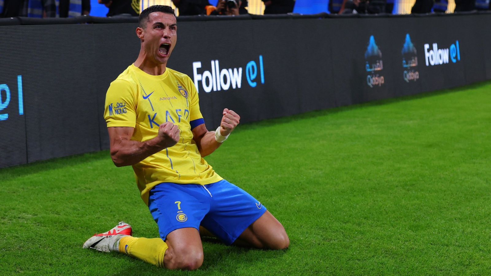  Cristiano Ronaldo is on his knees celebrating a goal with his arms in the air and mouth open.