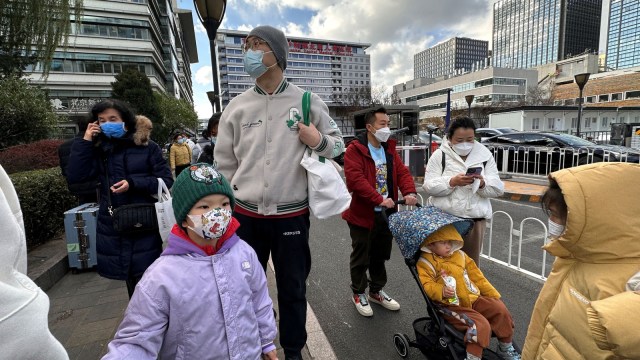 People and children leave a children's hospital in Beijing