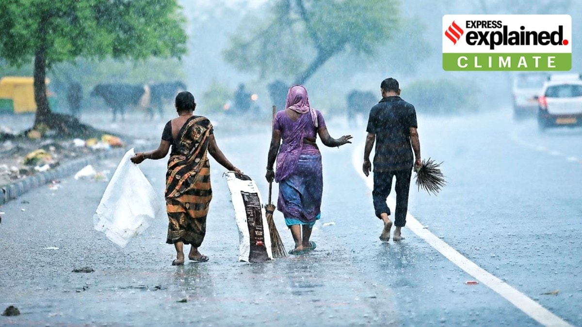 Women and a man walking during rains in Gujarat.