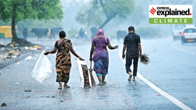 Women and a man walking during rains in Gujarat.