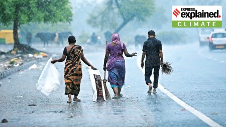 Women and a man walking during rains in Gujarat.