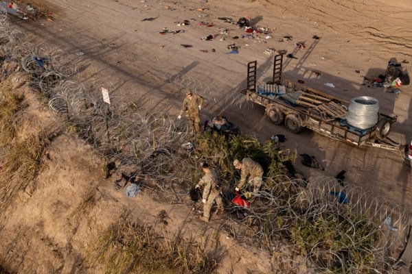 Members of the National Guard install concertina wire along the banks of the Rio Grande River to prevent migrants from crossing from Mexico into Eagle Pass, Texas, U.S.