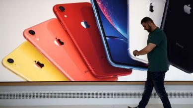 An Apple employee walking past a banner of iPhone SE