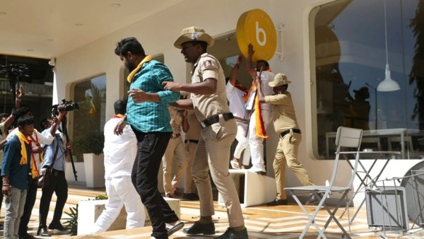 Protesters vandalising the signboard of the multi-city hotel chain Bloom, as policemen take them away for detention. 