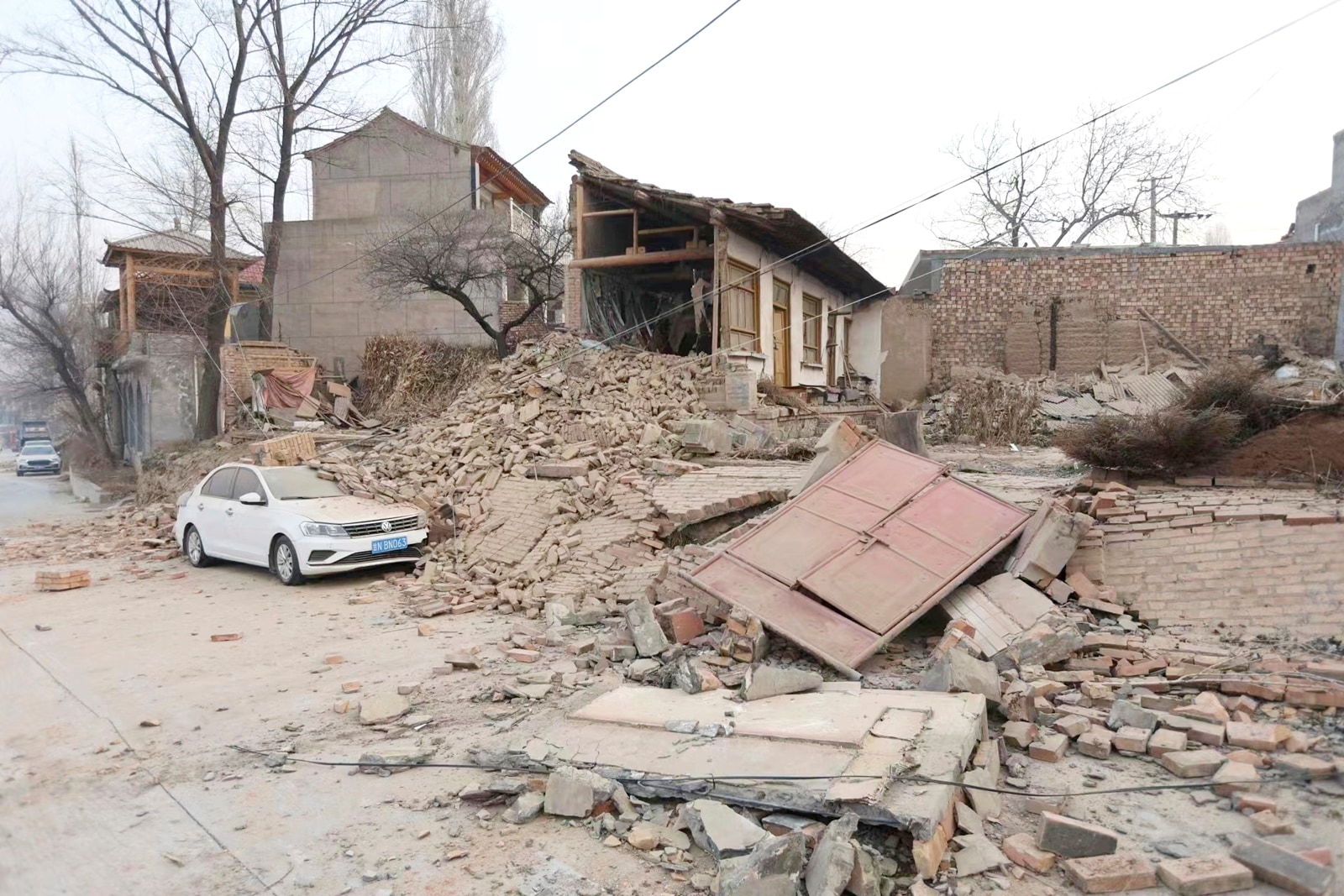 A vehicle is partially covered by a collapsed building in the aftermath of an earthquake in Dahejia village of Jishishan county in northwestern China's Gansu province Tuesday, Dec. 19, 2023. An overnight earthquake killed multiple people in a cold and mountainous region in northwestern China, the country's state media reported Tuesday.(Chinatopix via AP)