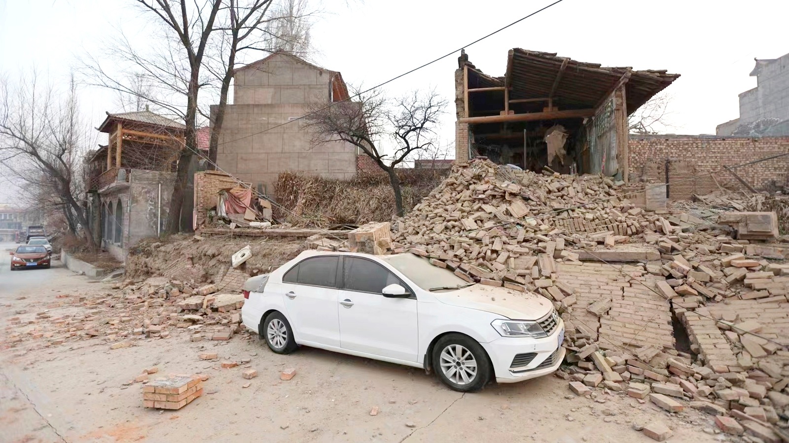 A vehicle is partially covered by a collapsed building in the aftermath of an earthquake in Dahejia village of Jishishan county in northwestern China's Gansu province Tuesday, Dec. 19, 2023. An overnight earthquake killed multiple people in a cold and mountainous region in northwestern China, the country's state media reported Tuesday.(Chinatopix via AP)