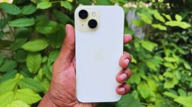 iPhone 15 against the backdrop of a garden.