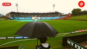 IND vs SA Live Score: A security guard holds an umbrella as the pitch and part of the ground is covered during rains a day before the first India vs South Africa Test match at SuperSport Park Cricket Stadium, in Centurion. (PHOTO: REUTERS)