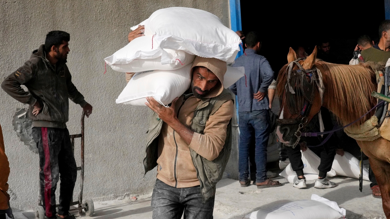 Palestinians take wheat from a U.N. distribution center in the Bureij refugee camp in the Gaza Strip on Sunday, Dec. 10, 2023. (AP Photo/Hatem Moussa)