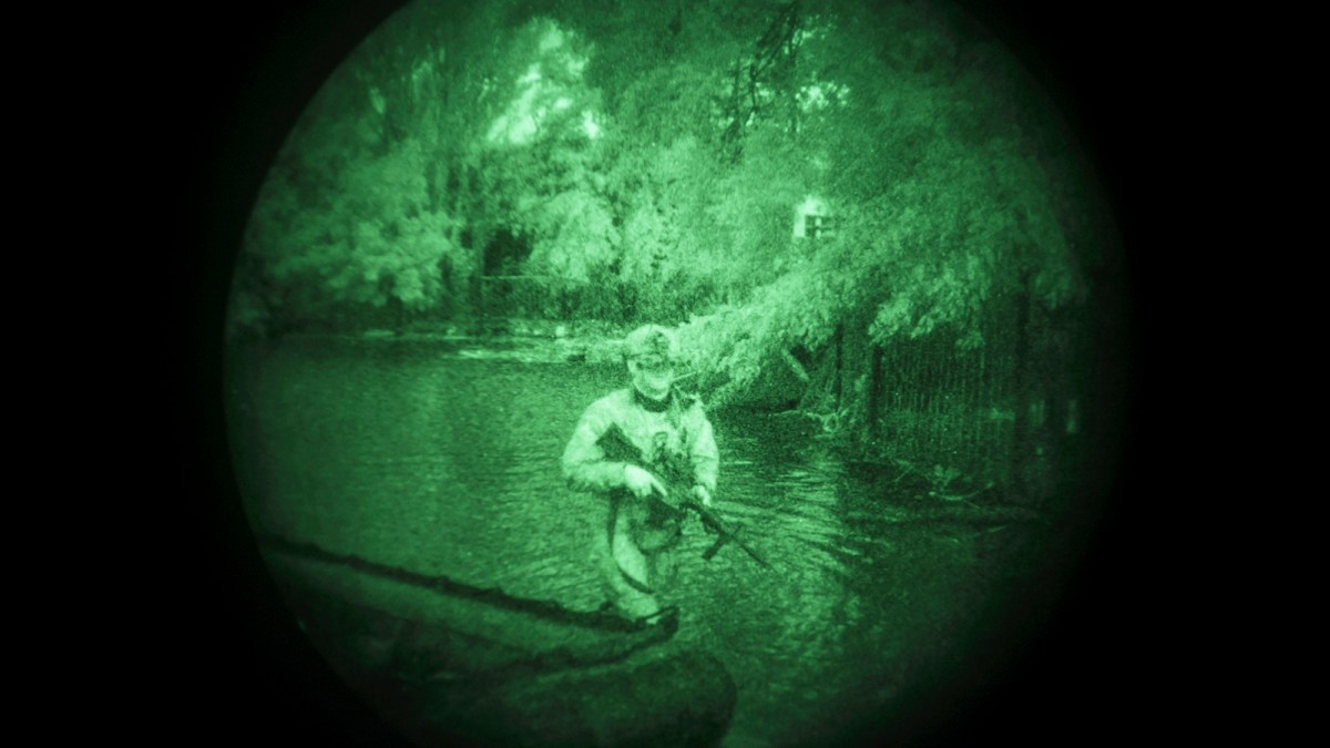A Ukraine Special Operations Forces soldier walks through water on the shores of the Dnipro River using night vision goggles, or NVG, during a night mission in Kherson region, Ukraine, Sunday, June 11, 2023. They transform themselves from nondescript civilians into elite fighters, some in wetsuits and some in boats. In the morning, when their operations end, they’re back to anonymity. (AP Photo/Felipe Dana)