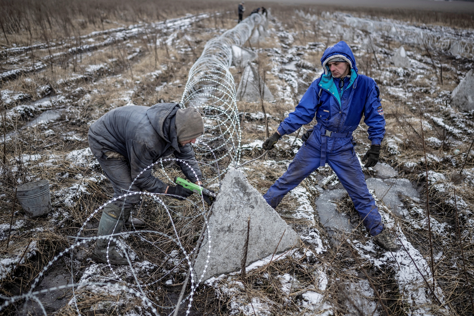 Workers install razor wire as a part of defence structures near a front line, amid Russia's attack on Ukraine, in the Kharkiv region, Ukraine December 25, 2023. REUTERS/Viacheslav Ratynskyi