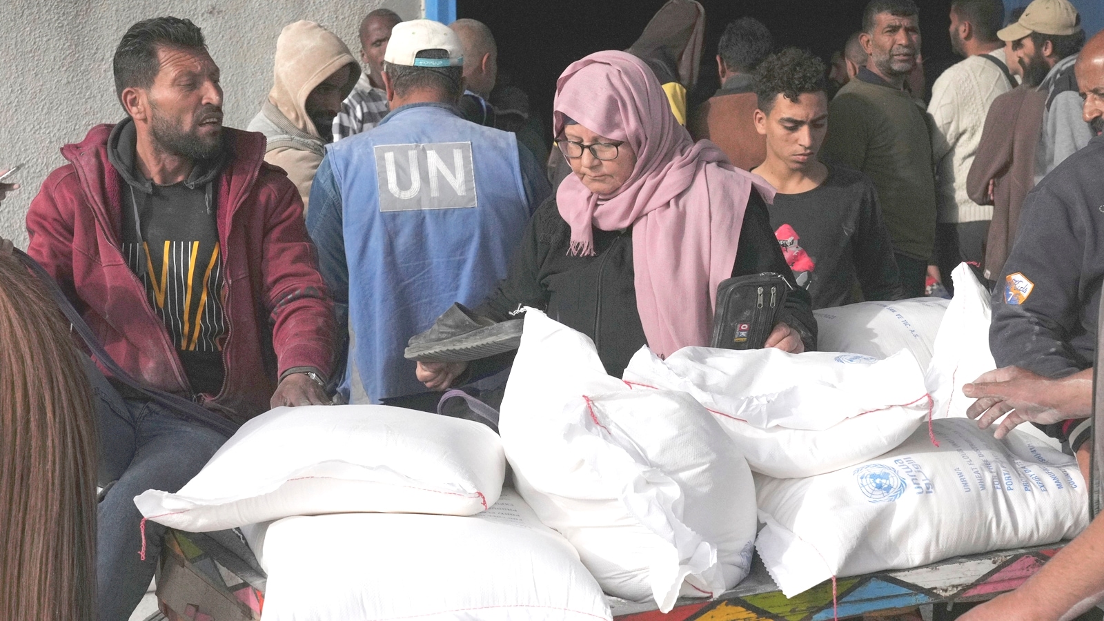 Palestinians take wheat from a U.N. distribution center in the Bureij refugee camp in the Gaza Strip on Sunday, Dec. 10, 2023. (AP Photo/Hatem Moussa)