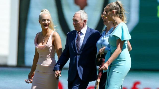 Former Australian cricket captain Allan Border walks with the daughters of former Australian cricketer Dean Jones, Phoebe, right, and Augusta, left, with their mother, Jane, centre, during a tribute for the late batsman who died suddenly in India, during the tea break on day one of the Boxing Day cricket test between India and Australia at the Melbourne Cricket Ground, Melbourne, Australia, Saturday, Dec. 26, 2020. (AP Photo/Asanka Brendon Ratnayake)