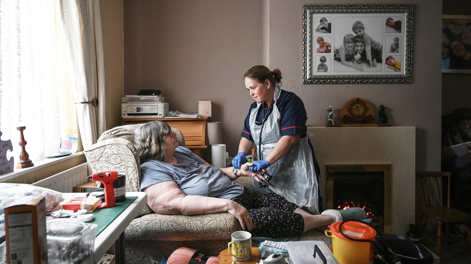 Vanessa Joyce, left, had her blood pressure taken and her heart rate checked at her home by an advanced community nurse practitioner, Samantha Hines, from the Jean Bishop Integrated Care Centre, in Hull, England on June 6, 2023. An “integrated care center” brings doctors, physiotherapists, social workers, and pharmacists under one roof. It won’t solve Britain’s underlying social care crisis — but it could help. (Mary Turner/The New York Times)