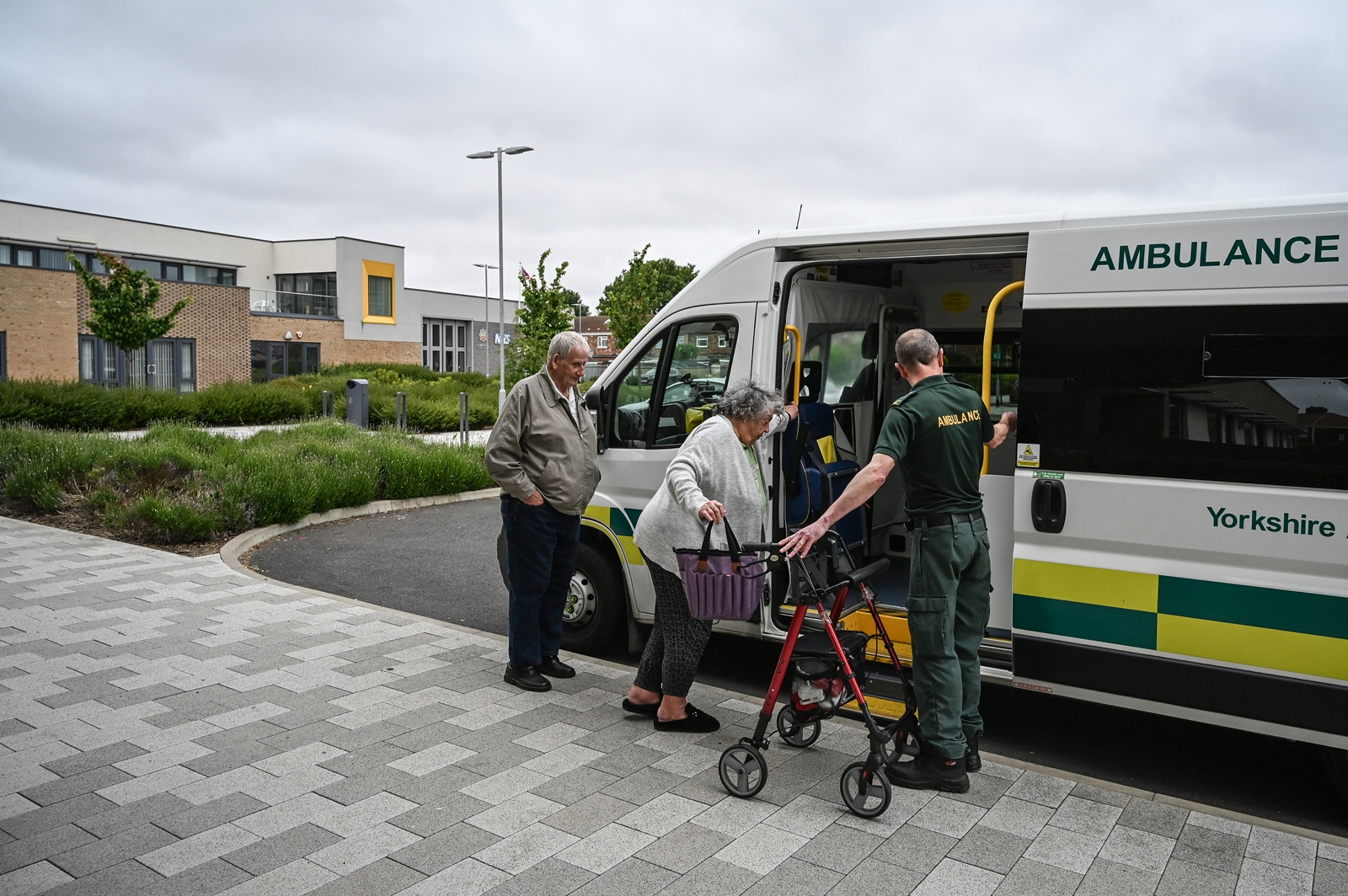 Norma Fitzgerald is helped into an ambulance at the Jean Bishop Integrated Care Center in Hull, England on June 1, 2023. An “integrated care center” brings doctors, physiotherapists, social workers, and pharmacists under one roof. It won’t solve Britain’s underlying social care crisis — but it could help. (Mary Turner/The New York Times)