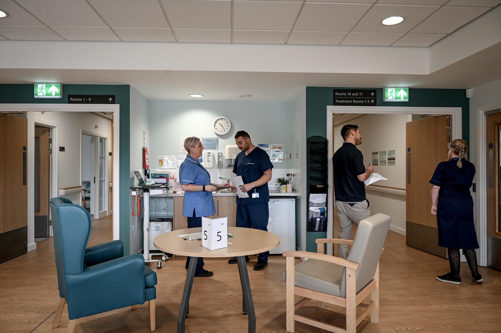 Staff members discuss patient care at a workstation in the Jean Bishop Integrated Care Center in Hull, England on June 1, 2023. An “integrated care center” brings doctors, physiotherapists, social workers, and pharmacists under one roof. It won’t solve Britain’s underlying social care crisis — but it could help. (Mary Turner/The New York Times)