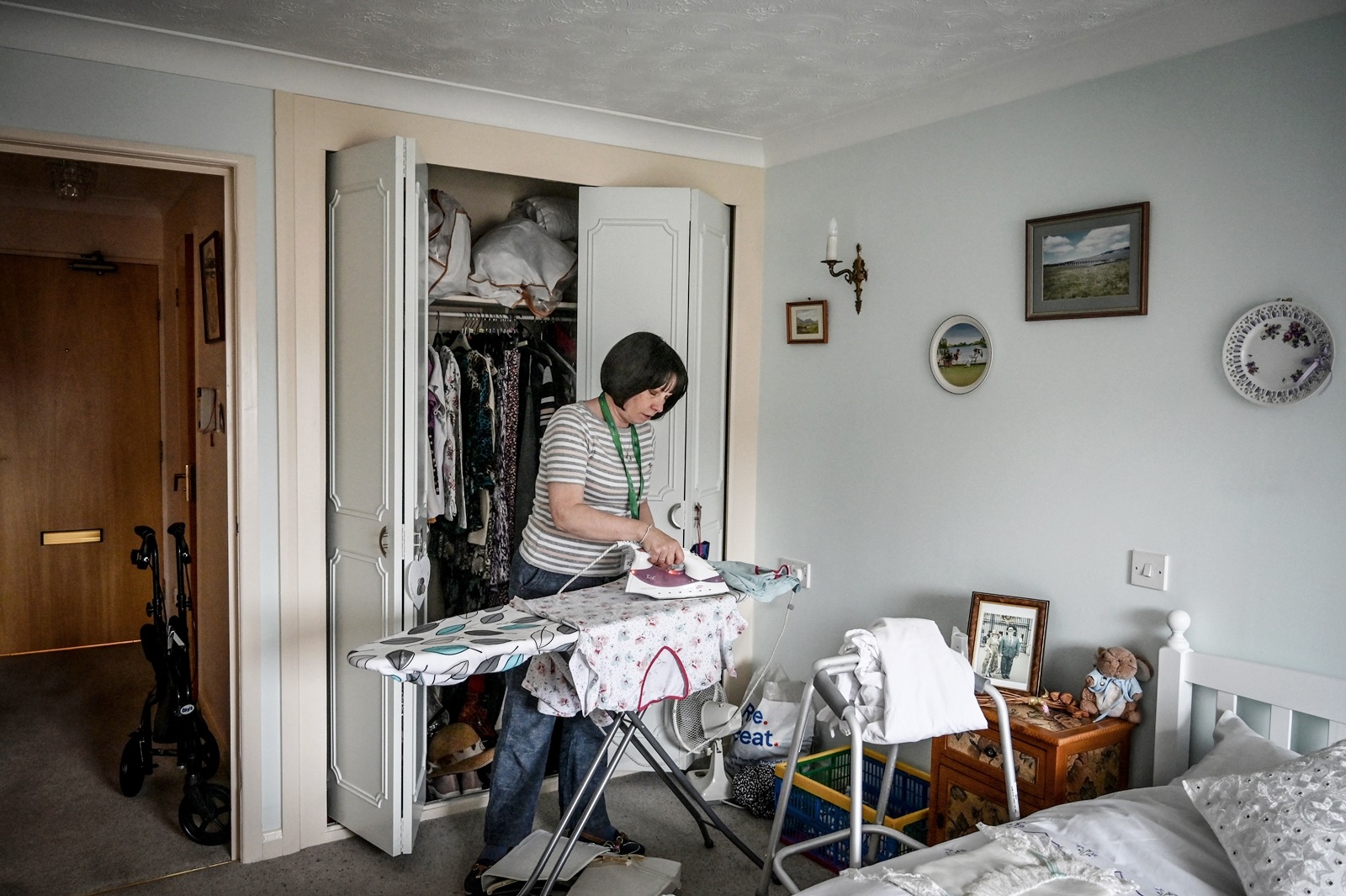 A home care worker, Linda Ryan, from Age UK, visits Mavis Ireland’s home to help with tasks such as ironing and making the bed, which Mavis finds difficult, in Hull, England on June 6, 2023. An “integrated care center” brings doctors, physiotherapists, social workers, and pharmacists under one roof. It won’t solve Britain’s underlying social care crisis — but it could help. (Mary Turner/The New York Times)