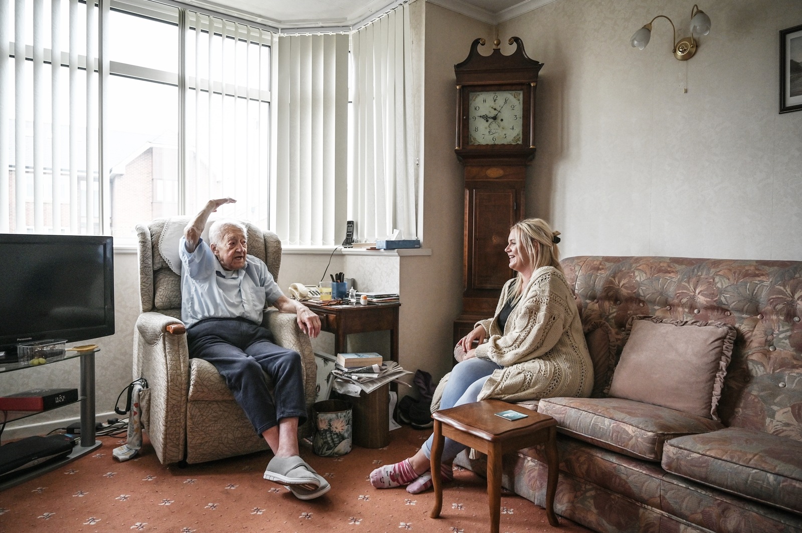 Alan Walker, left, during a social meeting with Lucy Henn, who volunteers for the charity Age UK, in Hull, England on May 30, 2023. An “integrated care center” brings doctors, physiotherapists, social workers, and pharmacists under one roof. It won’t solve Britain’s underlying social care crisis — but it could help.  (Mary Turner/The New York Times)