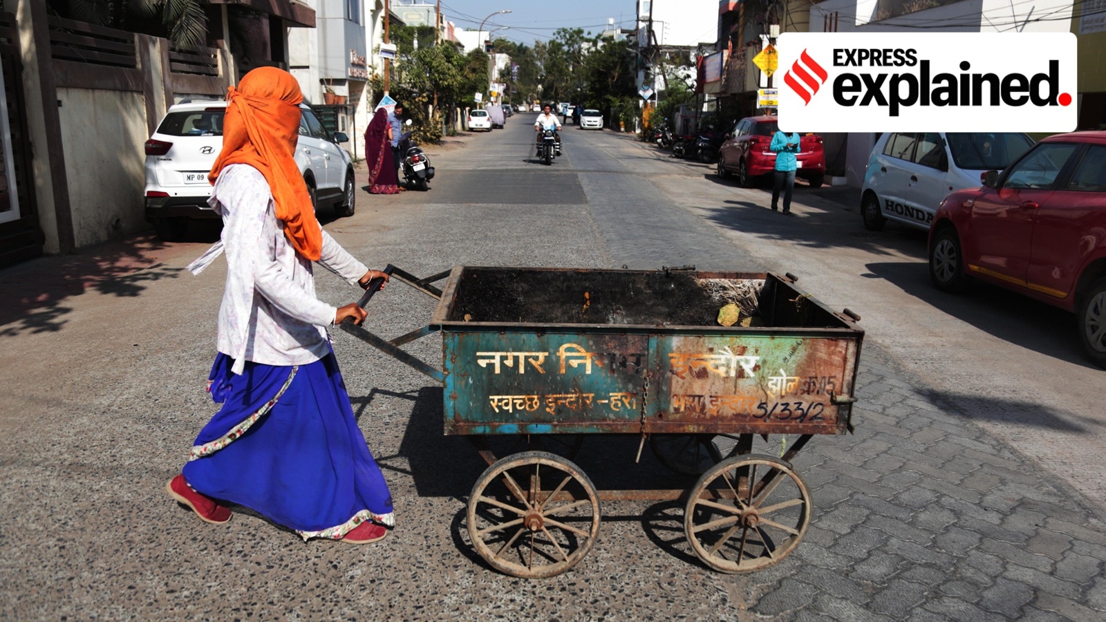 A safai mitra pulls a hand cart to collect trash on the road side in Indore.