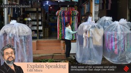 A worker of a garment shop, covering the dresses with plastics, hanging in a garment stand for sale infront of the shop in a rainy morning at Agartala, capital of the Northeastern state of Tripura, India.