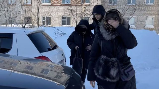A woman wearing a protective mask and sunglasses, believed to be Lyudmila Navalnaya, the mother of Russian opposition leader Alexei Navalny, is accompanied into a car as she leaves the IK-3 penal colony.