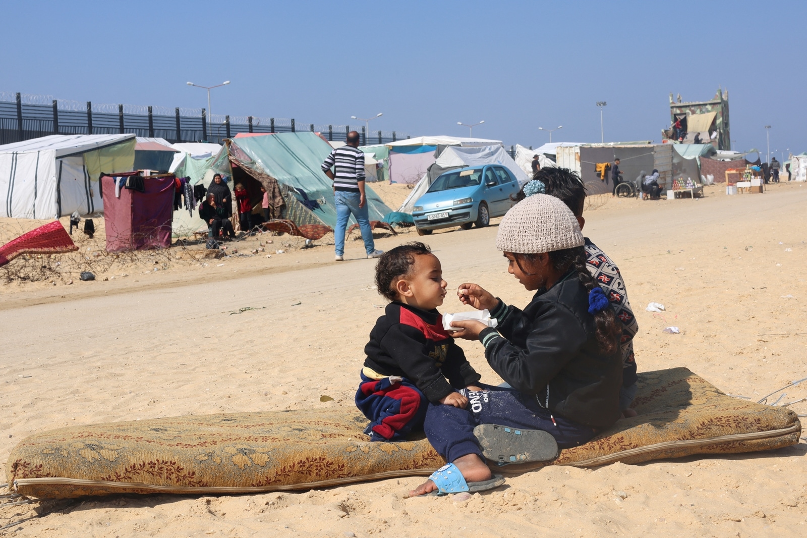 Displaced Palestinian girl, who fled her house due to Israeli strikes, feeds her brother at a tent camp, near the border with Egypt, in Rafah in the southern Gaza Strip, February 25, 2024. REUTERS/Saleh Salem