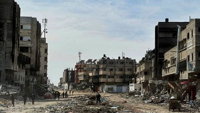 People walk near damaged houses at Zeitoun neighborhood after Israeli forces withdrew from the area, in Gaza City