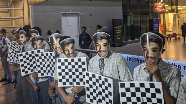 Schoolkids wearing facemasks of Gukesh at Chennai airport waiting to welcome the 17-year-old
