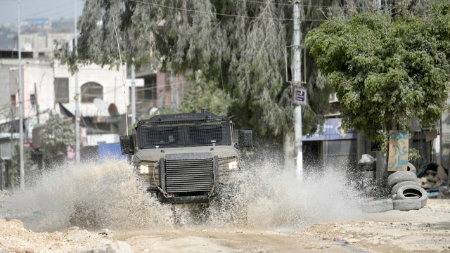 An Israeli military vehicle drives through water during a military operation in the nearby Nur Shams refugee camp, near the West Bank town of Tulkarem. (AP)