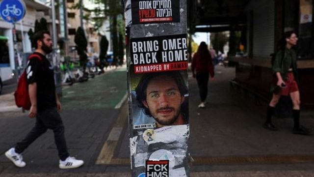 People walk past a poster of a hostage kidnapped during the deadly October 7 attack by Palestinian Islamist group Hamas from Gaza, pasted along with other items on a light pole in Tel Aviv, Israel. (Reuters Photo)