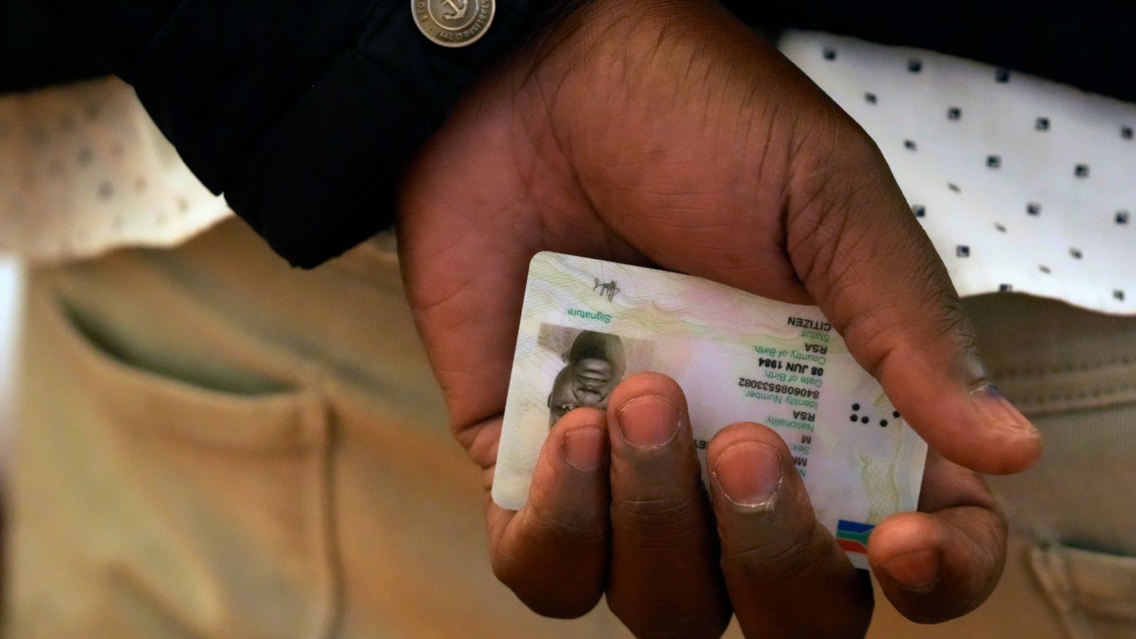 A man holds his ID before receiving ballot papers to cast his vote at a polling station in Alexandra, near Johannesburg, South Africa. (AP Photo)