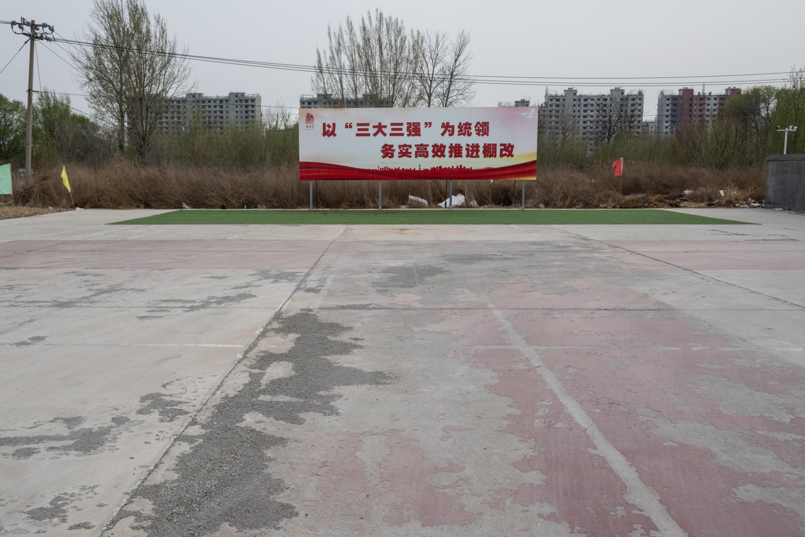 Um outdoor com slogans oficiais promovendo a renovação de “favelas” no local de uma vila demolida em Zhangjiawan, um subúrbio de Pequim, 3 de abril de 2024. (Gilles SabriŽ/The New York Times)