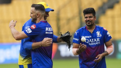 Royal Challengers Bengaluru captain Faf du Plessis greets Chennai Super Kings head Coach Stephen Fleming as Karn Sharma looks on during a training session ahead of the Indian Premier League (IPL) 2024 cricket match against Chennai Super Kings, at M Chinnaswamy Stadium in Bengaluru