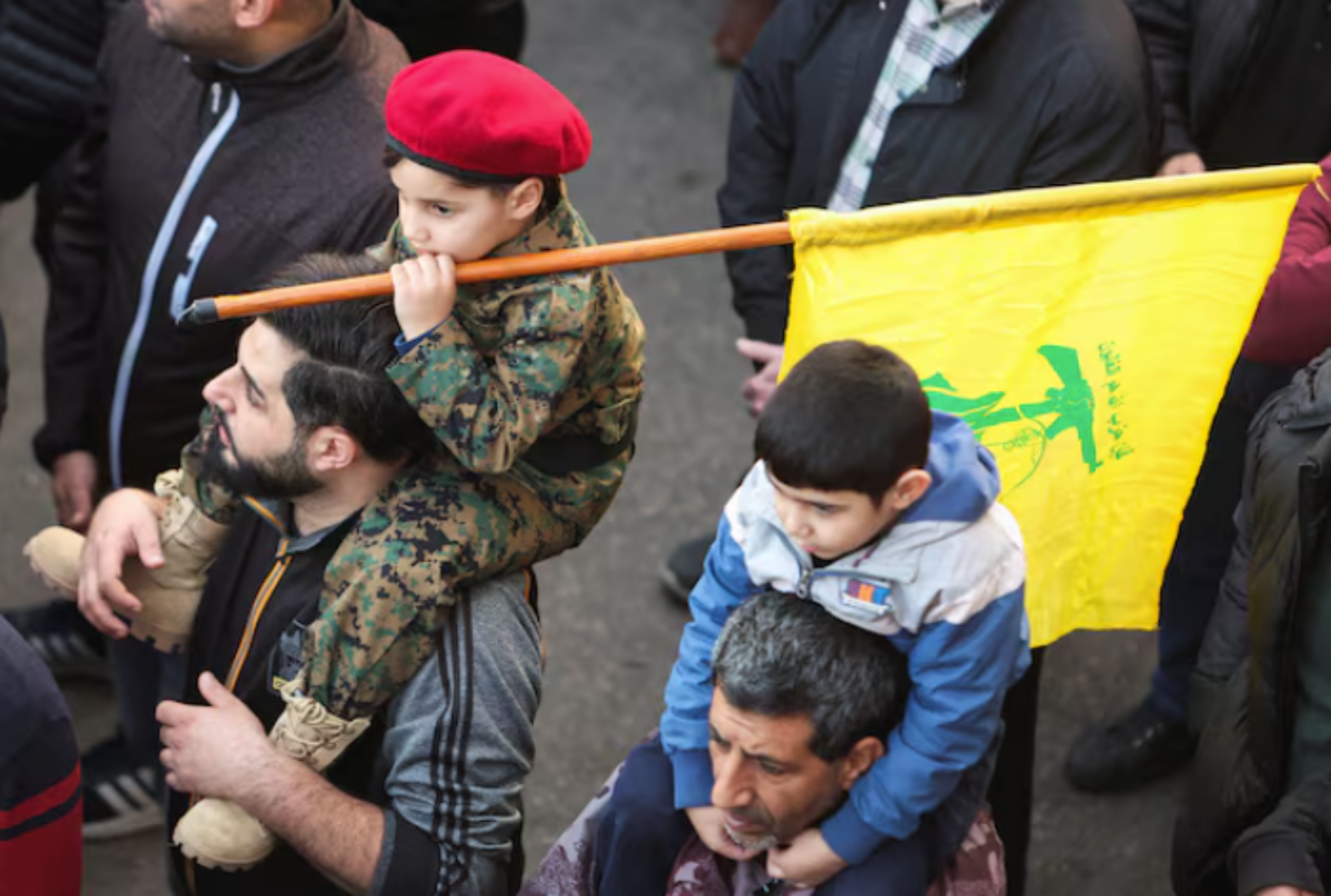 2023 年 12 月在以色列袭击中丧生的真主党成员的葬礼上，一名儿童举着真主党旗帜（路透社）