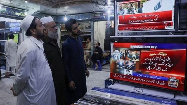 Men watch television screens as they wait to see the appearance of the jailed Pakistan's former Prime Minister Imran Khan, expected to be streamed live during a video proceeding of the Supreme Court of Pakistan, at a market in Peshawar,