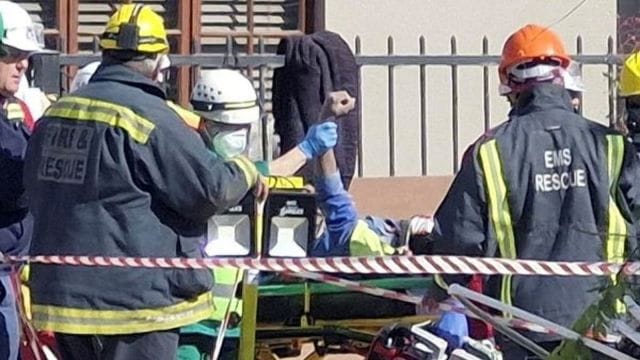 A man raises his hand as rescue workers carry him to an ambulance after being rescued having survived 118 hours after a deadly building collapse in George, South Africa