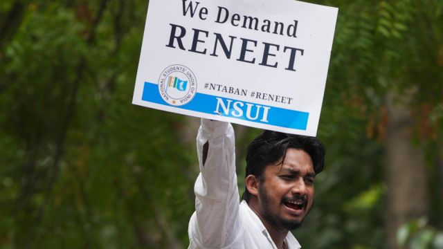 An NSUI activist holds a placard during ‘Chhattra Sansad Gherav’ protest at Jantar Mantar against the alleged irregularities in NEET-UG and cancellation of UGC-NET exams, in New Delhi. (PTI)