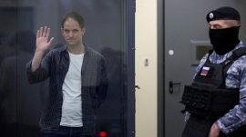 Wall Street Journal reporter Evan Gershkovich, who is in custody on espionage charges, waves behind a glass wall of an enclosure for defendants as he attends a court hearing in Moscow, Russia, April 23, 2024