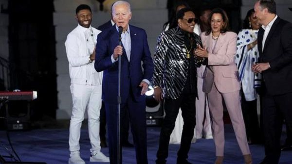 US President Joe Biden speaks on stage accompanied by Charlie Wilson and US.  Vice-President Kamala Harris during a Juneteenth concert on the South Lawn at the White House in Washington