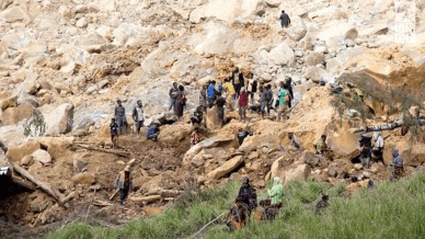 People clear an area at the site of a landslide in Yambali village,