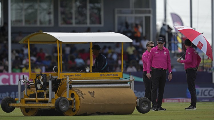 Umpires inspect the field as they stand next to a super sopper after rain stopped play during the ICC Men's T20 World Cup second semifinal cricket match between England and India at the Guyana National Stadium in Providence, Guyana