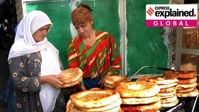 Two Tajik women in headscarves negotiating over bread.
