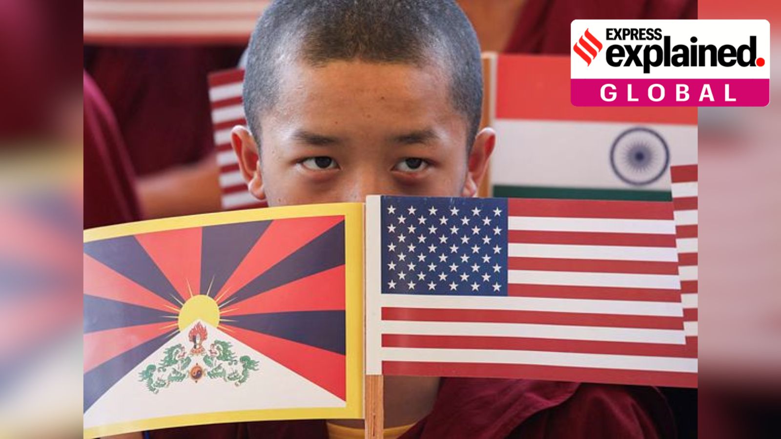 A young Tibetan monk holding up US Tibet flags