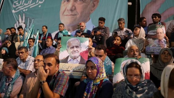 Supporters hold posters of Iranian presidential candidate Masoud Pezeshkian during a campaign event in Tehran, Iran. (Reuters)